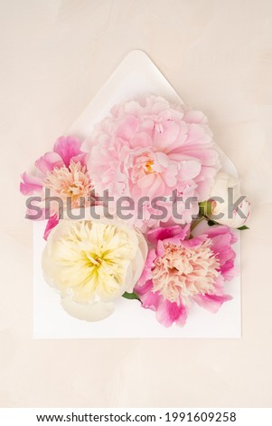 Beautiful fresh peony blooms in an envelope floral flat lay