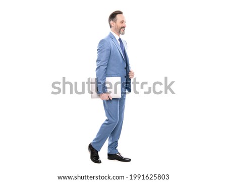 happy grizzled businessman in suit full length walking with computer isolated on white, business