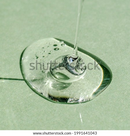 A drop of transparent cosmetic gel on a green background.
