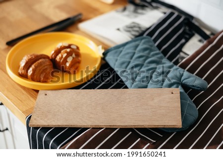 Croissant, hot gloves and wooden pads on the minimal wood table. A picture of a kitchen in a bakery. background and copy space.