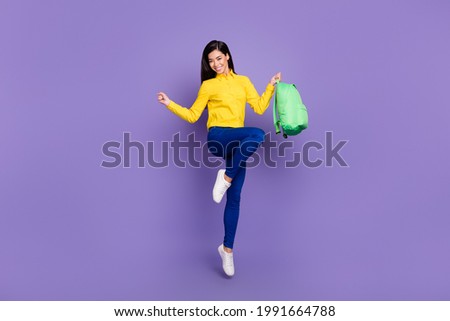 Full size photo of attractive young woman jump up winner hold backpack isolated on purple color background