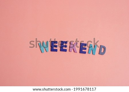 Wooden letters spelling the word "WEEKEND" on sweet background.