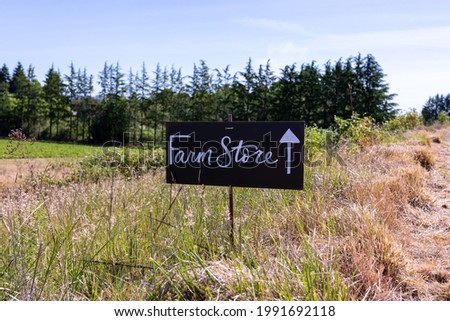A farm sign on a small blackboard on a single pole read "Farm Store" next to a pointing arrow   