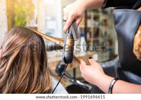 hairdresser doing curls to a client, brown hair with blonde highlights in the hair salon. beauty salon