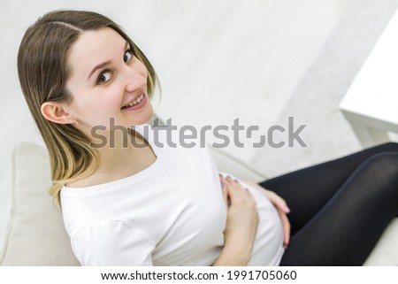 Photo of cute pregnant woman looking at the camera.