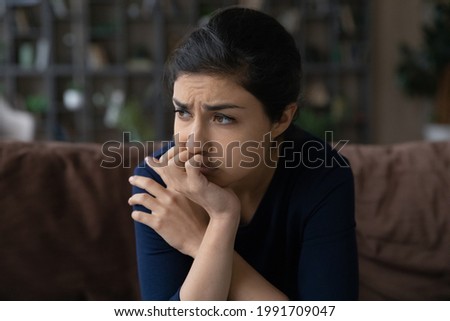 Pessimistic view. Confused indian woman sit on couch with sad look hurt with cheating of beloved man friend betrayal think what to do. Anxious teen female having relationship love problem heartbreak Royalty-Free Stock Photo #1991709047