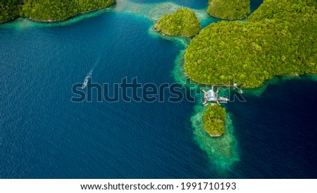 Top view picture of a lagoon in sohoton cove, socorro, philipines, with a house surrounded by turquoise blue water located on the right side, some boats and impressive green hills
