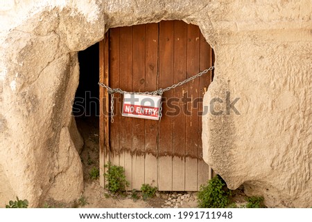 Old wooden door, entrance to the cave, with the inscription "no entry", hanging on a chain with a lock, the concept of restrictions.
