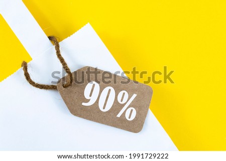 White paper shopping bag with 90% discount on yellow background.