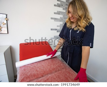 the beautician puts a disposable sheet on the couch	