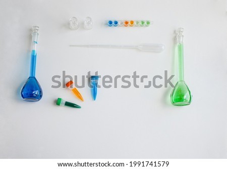 Set of school supplies for biology or chemistry lesson on light background: glass flasks, tweezers, pipette, plastic tubes with Cu and Co salts. Concept: back to school. Flatlay, top view.