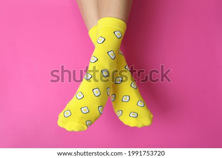 Female legs in funny socks on pink background Royalty-Free Stock Photo #1991753720