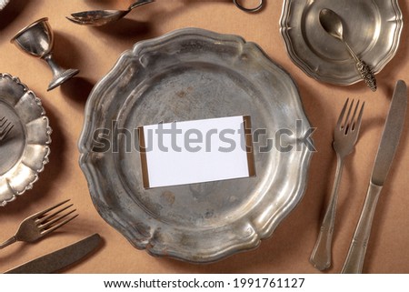 Dinner invitation mockup with an RSVP card, shot from the top on a vintage silver salver with other elegant tableware and cutlery, overhead flat lay mock up for a formal occasion Royalty-Free Stock Photo #1991761127