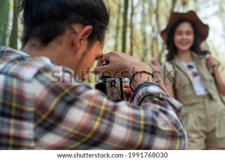 Male and female tourists are touring nature and taking pictures of the scenery. Couples go wild together on weekends. Nature tourism concept.