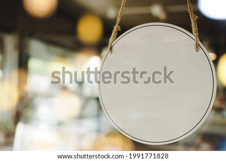 empty wooden sign board hanging on glass door with bokeh light in modern cafe restaurant, copy space for text advertising, cafe restaurant, advertisement marketing and small business owner concept