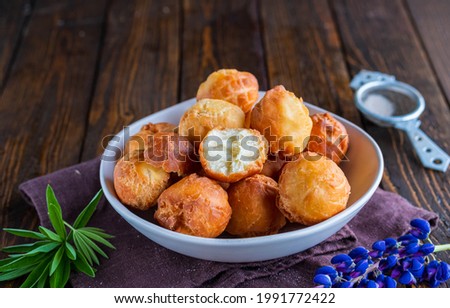 Round fried donuts in a ceramic bowl on a brown wooden background. Baking in oil.
