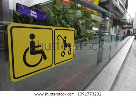 a ramp with glass railing and signage for wheelchairs and strollers.