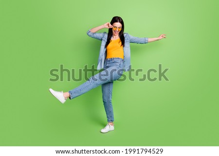 Full size photo of happy cheerful pretty lovely woman in sunglass silly dancing isolated on green color background