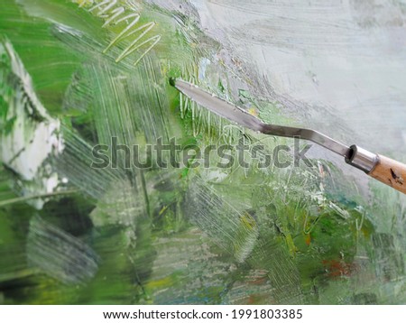 Woman Artist painting abstract oil painting in art studio. Close up photo palette knife in hand on canvas background. Modern art, creativity concept, hobby