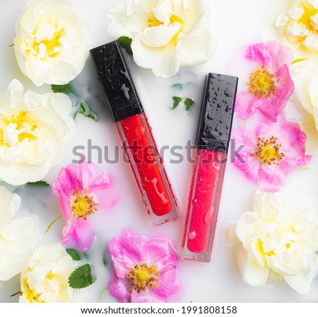 Lip gloss and rose. Lipstick. Beautiful lips. Decorative cosmetics . Well-groomed face. Makeup. Cosmetics without labels. Flowers