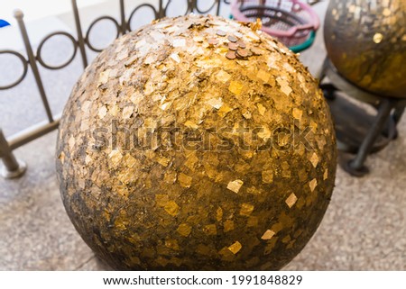 Gold sheet pasting on concrete balls in a temple in Thailand