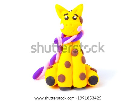 Giraffe with a lilac scarf from air plasticine isolated on a white background. Children's creativity