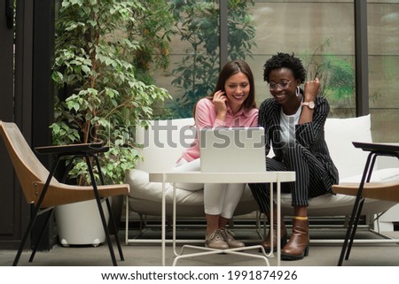 Two female colleagues are discussing some new business plans while sitting in the foyer of the company's building. Royalty-Free Stock Photo #1991874926