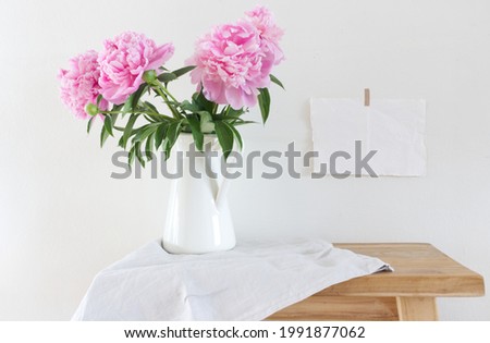Peony flowers in a white vase on old wooden table background. With copy space for greeting message. Spring flowers. Spring background. Valentine's Day and Mother's Day background.                  