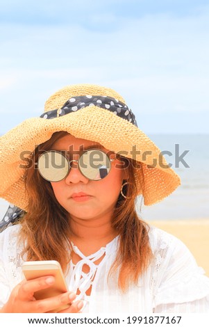 Asian woman use cellphone at beach to working and travel on vacation in summer season. Enjoy on holidays in tropical island. Lifestyle of new young girl with technology.