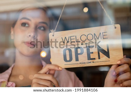 Smiling young asian business owner, employee retail,coffee shop woman,girl turning,setting sign board to open for welcome customer, reopen store after close lockdown quarantine in covid.Label concept.