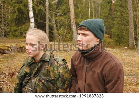 guy and a girl are standing side by side in nature.