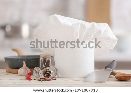 Chef's hat, utensils and products on table in kitchen
