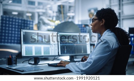 Female Engineer uses Computer to Analyse Satellite, Calculate Orbital Trajectory Tracking. Aerospace Agency International Space Mission: Scientists Working on Spacecraft Construction. Over Shoulder Royalty-Free Stock Photo #1991920121
