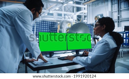 Managing Engineer and Chief Technician Working on Satellite Construction, Talk, Use Green Screen Computer. Aerospace Agency Manufacturing Facility: Scientists Assemble Spacecraft for Space Mission