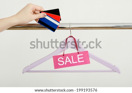 Unrecogniazible woman hand shopping with credit cards on sale.  Empty hanger on a rack of clothes with the sale sign. 