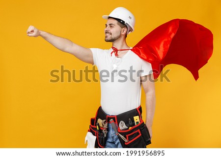 Powerful employee handyman man in red superhero suit helmet hardhat makes fly gesture isolated on yellow background studio Real heroes defend you. Instruments renovation apartment room Repair concept