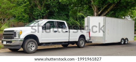 White pickup truck and large utility trailer parked on residential city street. Royalty-Free Stock Photo #1991961827
