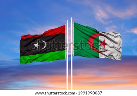 Algeria and Libya flags against of blue sky

