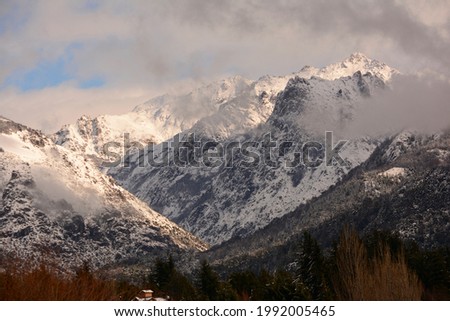 snowy mountains in the Andes mountain range, with foggy forest and clouds