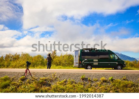 Camper van in summer norwegian landscape and drone pilot or stock photographer flying high technology drone. Lofoten archipelago Norway. Tourism vacation and travel. Explore nature
