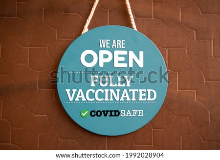 We are open and fully vaccinated sign in shop front. Royalty-Free Stock Photo #1992028904