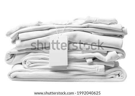 Stack of new white clothes with a blank garment tag isolated on white background Royalty-Free Stock Photo #1992040625