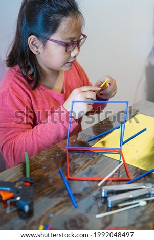 A young girl is constructing with lots of colorful plastic sticks. fun with building geometric figures and learning mathematics at home. homeschool.