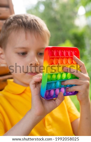 boy of seven with rainbow pop it