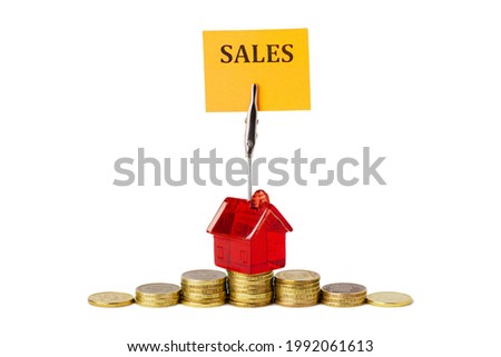 A small, red toy house with an orange sales sign stands on a pyramid of yellow, gold coins. The concept of the economic growth of sales in the real estate market, mortgage and capital. Isolated