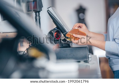 Process of barcode scanning on a goods in a shop, saleswoman selling a handbag to a customer