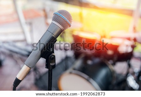 Electronic microphone on background of musical instruments drums with glare of sun, concept of summer vacation concert.