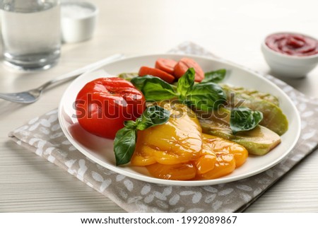 Delicious grilled vegetables with basil on white wooden table, closeup