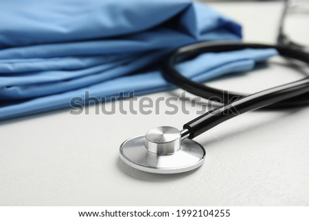 Stethoscope and medical uniform on white background, closeup