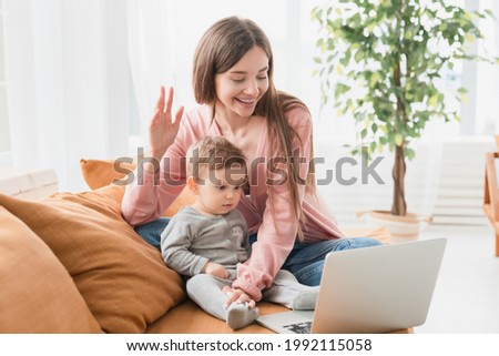 Happy young mother with toddler infant newborn baby having video call online conference conversation with relatives doctor pediatrician, having consultation remotely, communicating with friends